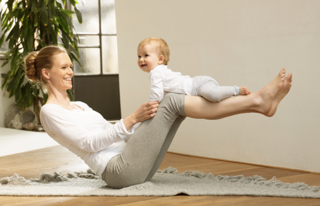 Mom balancing baby on knees.