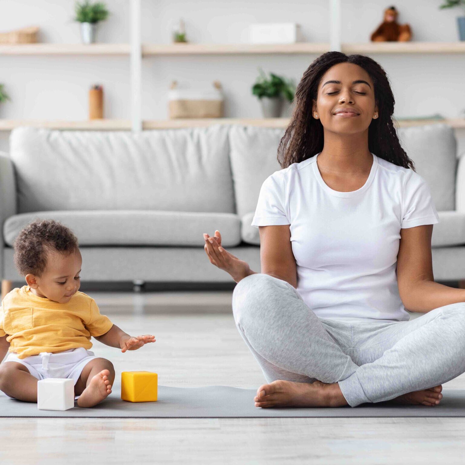 Mental Wellness Concept. Calm Happy Black Mother Meditating With Baby At Home