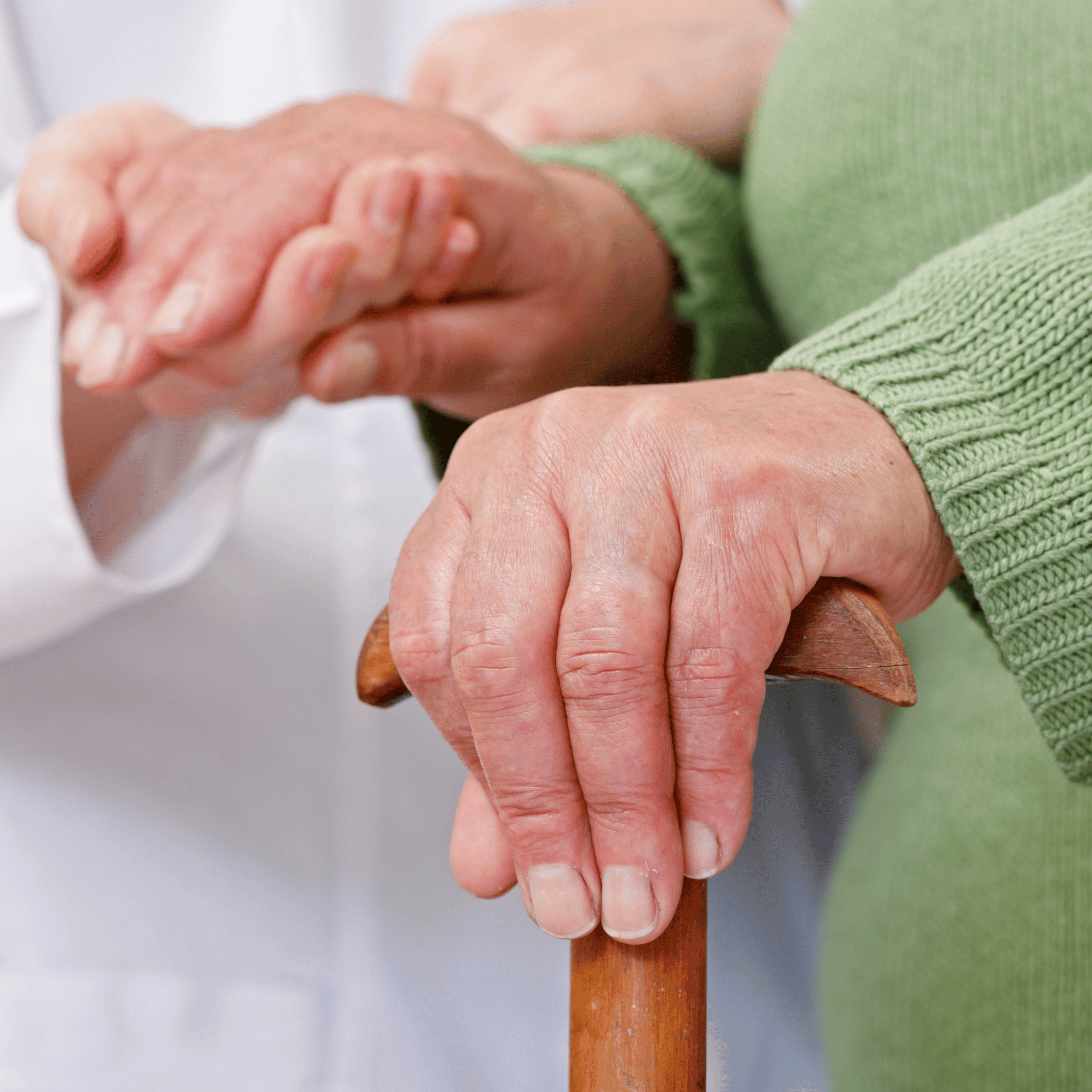 Photo for Physical Therapy can help Treat Arthritis Pain Blog Physical therapist in a white coat holding the hand of a patient who is suffering with arthritis and is using a cane to stabilize themself